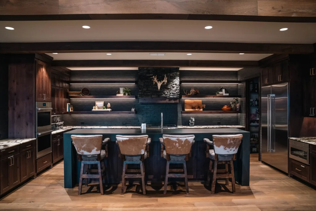 Custom dark-wood hunting lounge bar with illuminated shelving and island seating at Crown Point Ranch