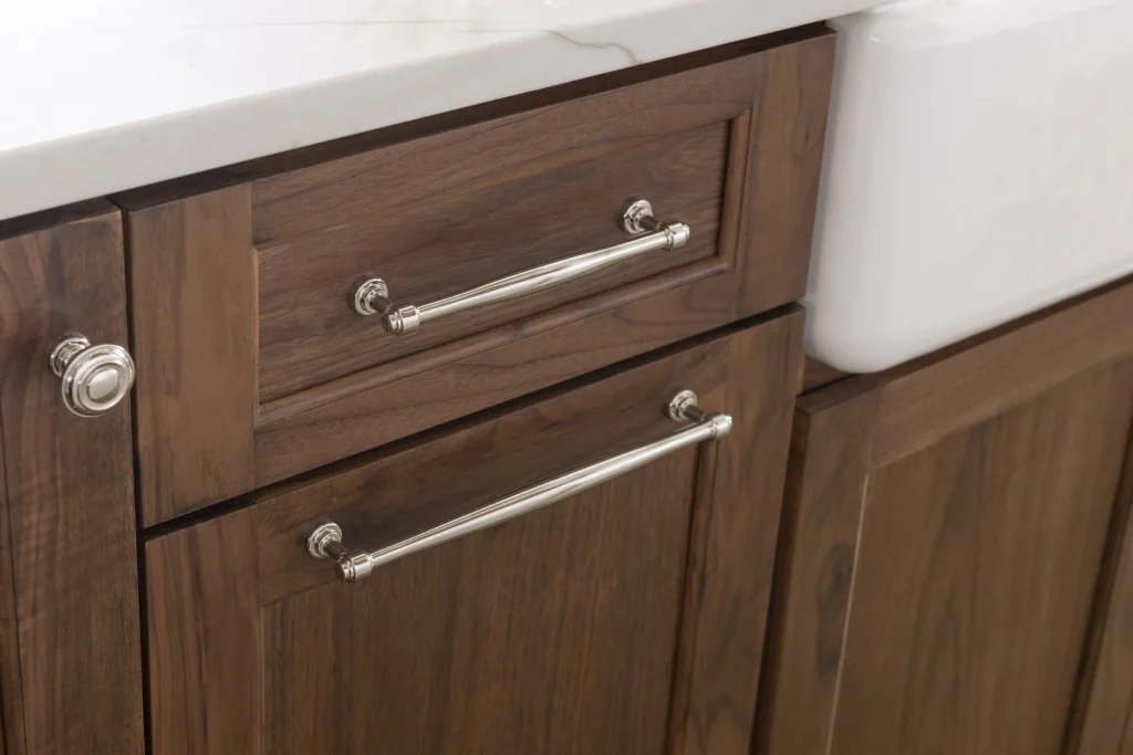 Walnut cabinet drawers with polished hardware beside a farmhouse sink