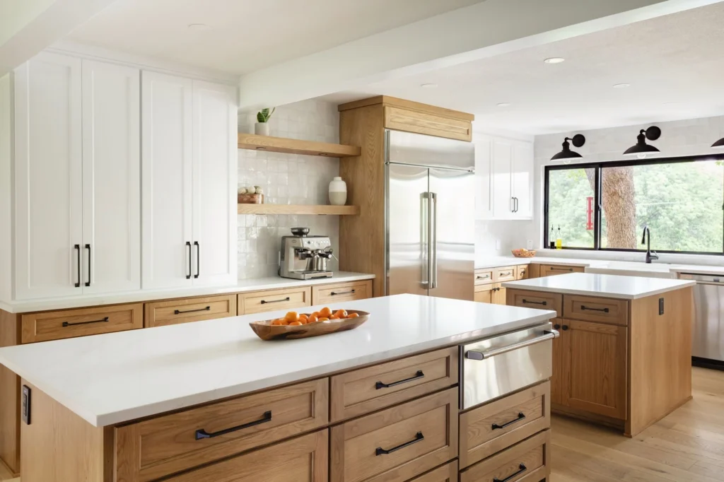 Two-tone kitchen with natural wood islands, white cabinetry, and large windows in the Frontier Project