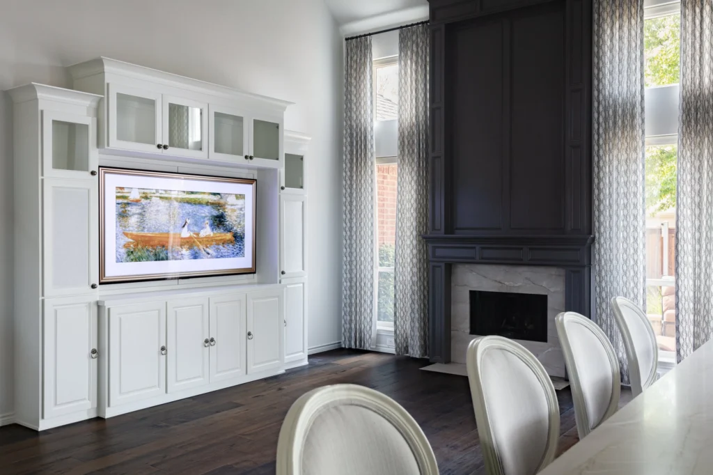Dining and living area with white media cabinetry, dark fireplace, and tall windows in Gulf Breeze