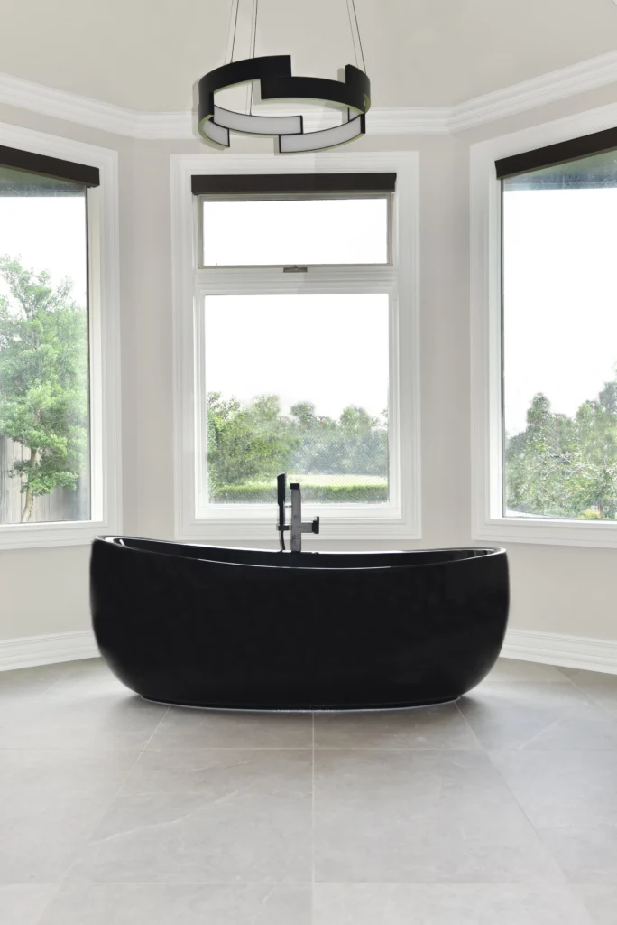 Black freestanding bathtub framed by tall windows in the Harbor Town II bathroom remodel