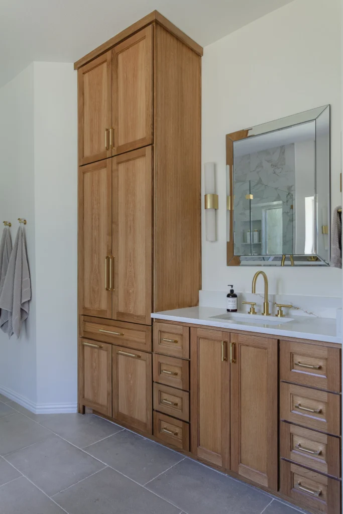Natural wood bathroom vanity with white countertop and glass shower in the Park Place II remodel