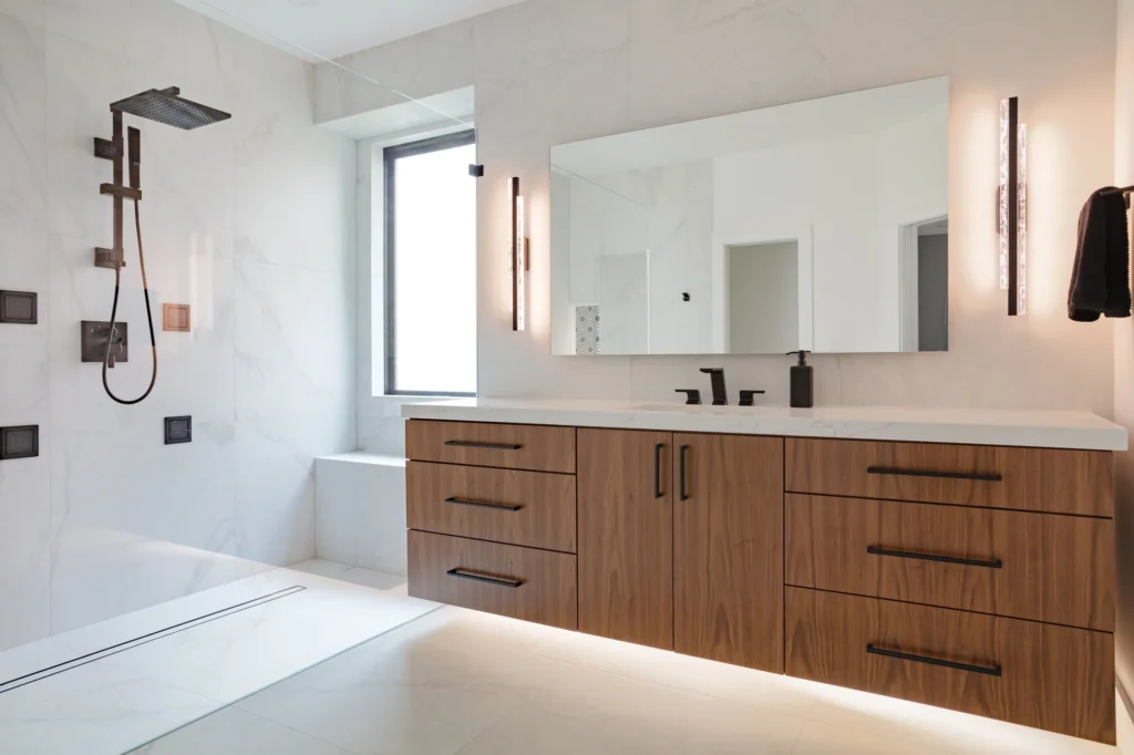 Modern primary bathroom with wood vanity, freestanding tub, and glass shower in Pintail