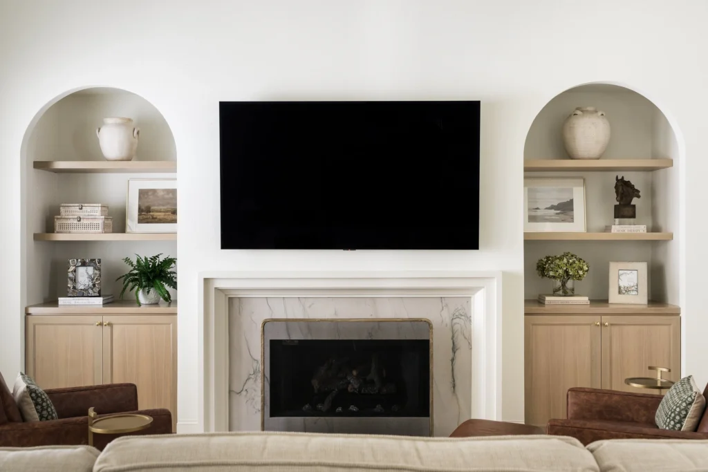 Refined living room with fireplace and arched built-in shelving in the Southlake Hills remodel